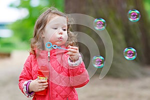 Cute little girl having fun with soap bubbles