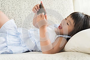 Cute little girl having fun to play game on smart phone