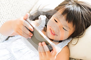 Cute little girl having fun to play game on smart phone