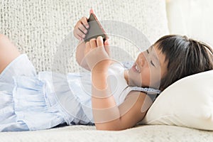 Cute little girl having fun to play game on smart phone