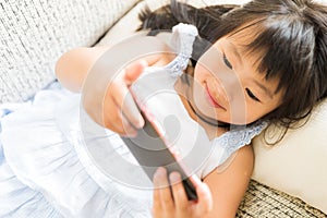 Cute little girl having fun to play game on smart phone