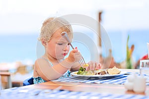 Cute little girl having lunch in resort restaurant