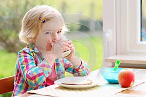 Cute little girl having toast and milk for breakfast