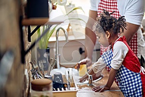 Cute little girl helping her father with the dishes in a domestic kitchen, washing dishes together, working as a team