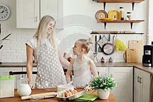 Cute little girl helps mom bake cookies in the kitchen