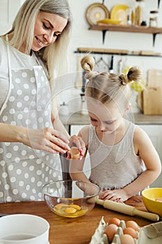 Cute little girl helps mom bake cookies in the kitchen