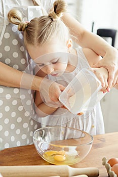 Cute little girl helps mom bake cookies in the kitchen