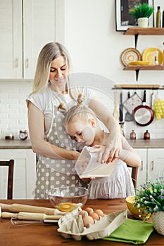 Cute little girl helps mom bake cookies in the kitchen