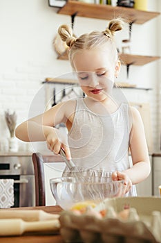 Cute little girl helps mom bake cookies in the kitchen