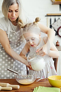 Cute little girl helps mom bake cookies in the kitchen