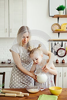 Cute little girl helps mom bake cookies in the kitchen