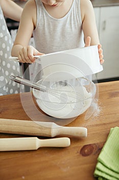 Cute little girl helps mom bake cookies in the kitchen