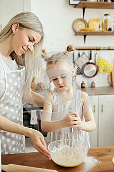 Cute little girl helps mom bake cookies in the kitchen