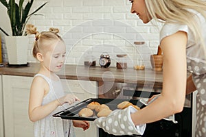 Cute little girl helps mom bake cookies in the kitchen