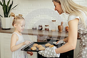 Cute little girl helps mom bake cookies in the kitchen