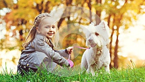 Cute little girl with her dog in autumn park. Lovely child with dog walking in fallen leaves. Stylish little girl enjoying colourf