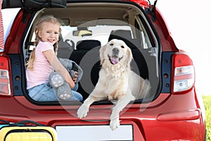 Cute little girl  her dog in open car trunk