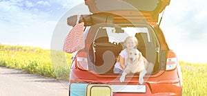 Cute little girl and her dog in open car trunk outdoors. Space for text