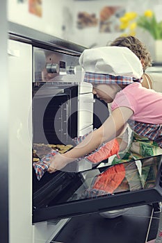 Cute little girl with her mother baking cookies in oven