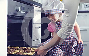 Cute little girl with her mother baking cookies in oven