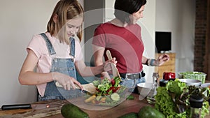 cute little girl and her mother cooking a vegetable salad together for family