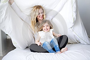 Cute little girl and her mother lying on a bed