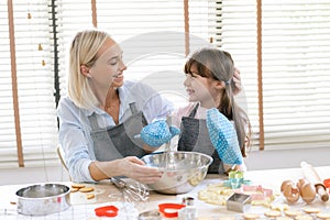 Cute little girl and her mother preparing the dough in the kitchen at home.Happy family and people concept.Mother`s day