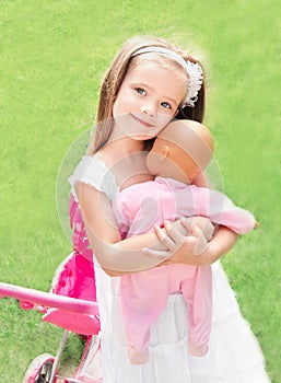 Cute little girl with her toy carriage and doll