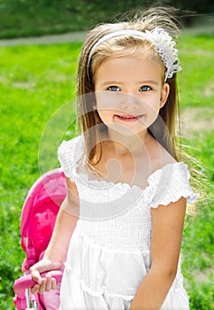 Cute little girl with her toy carriage and doll