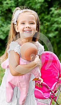 Cute little girl with her toy carriage and doll