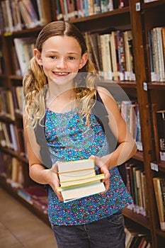 Cute little girl holding books in library