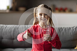 Cute Little Girl Holding Glass Of Water And Showing Thumb Up