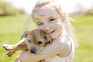 Cute little girl holding her funny boxer dog
