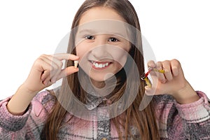 A cute little girl is holding her molar tooth in one hand and holding a colorful orthodontic appliance in the other hand. Studio