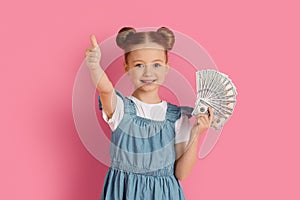 Cute Little Girl Holding Money Cash And Showing Thumb Up At Camera