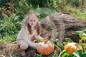 Cute little girl holding a pumpkin on a pumpkin patch