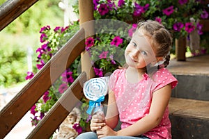 Cute little girl holding white and blue lollipop