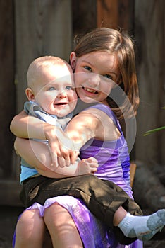 Cute little girl holds a baby boy and smiles