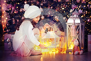 Cute little girl with holiday lantern near Christmas tree