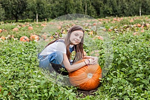 Cute little girl with huge pumpkin in a pumpkin patch