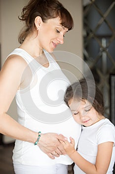 Cute little girl hugging her mother belly