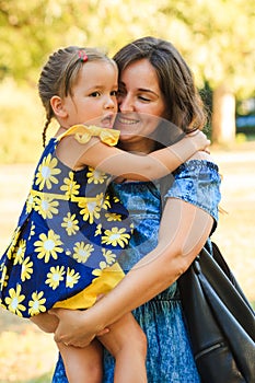 Cute little girl hugging her mother outdoor shot in park