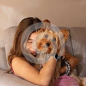 Cute little girl hugging her precious pet Yorkie and enjoying the moment.
