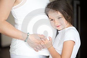 Cute little girl hugging her pregnant mother belly