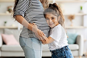Cute little girl hugging her pregnant mother big belly