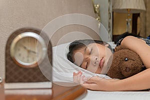 Cute little girl hugging teddy bear sleeping lay in  bed