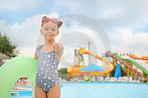 Cute little girl with inflatable ring near pool in water park