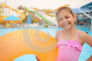 Cute little girl with inflatable ring near pool in water park
