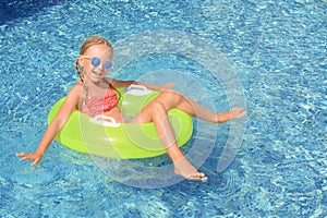 Cute little girl with inflatable ring in pool on sunny day