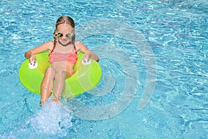 Cute little girl with inflatable ring in pool on sunny day. space for text